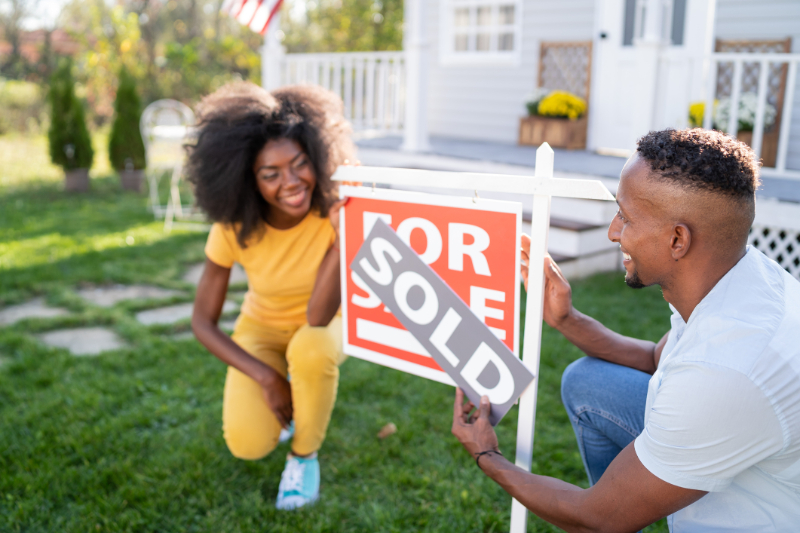 A couple changing home for sale sign to sold